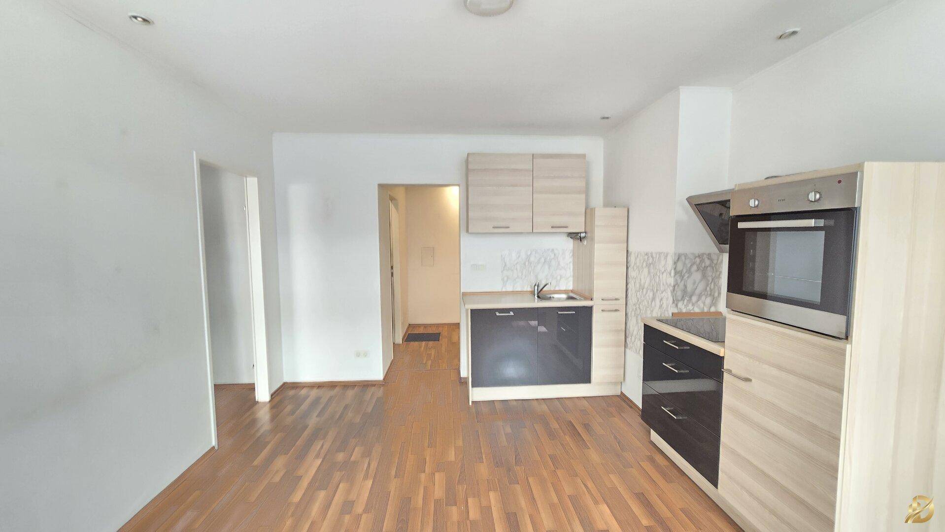 Offene Küchenzeile mit modernen Holz- und Anthrazitfronten in einem hellen Raum.