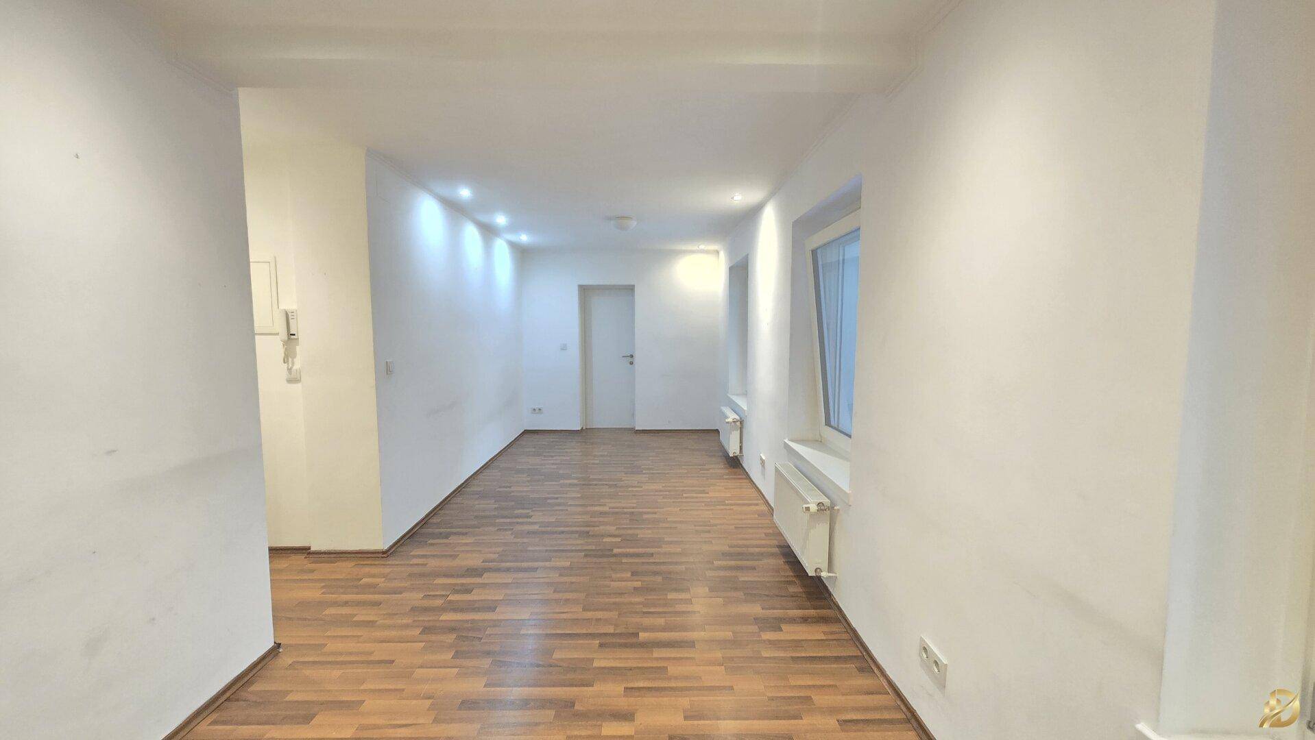 Langer, heller Flur mit Parkettboden und Fenstern, der viel Tageslicht bietet.