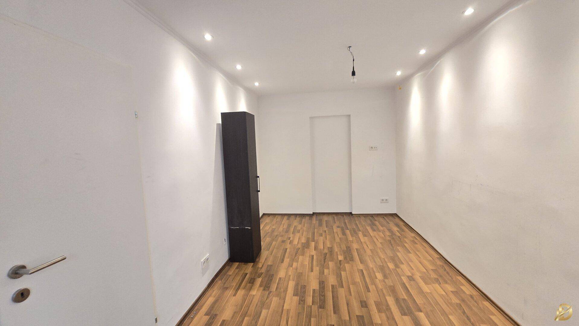 Leeres Zimmer mit Parkettboden und weiß gestrichenen Wänden, bereit zur Einrichtung.