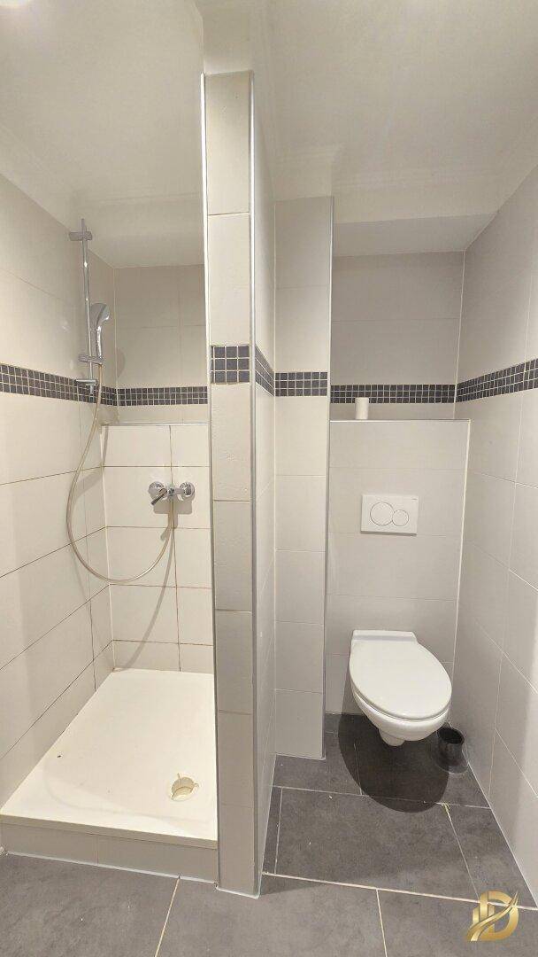 Modernes Badezimmer mit Duschbereich und wandhängendem WC in neutralen Farben.