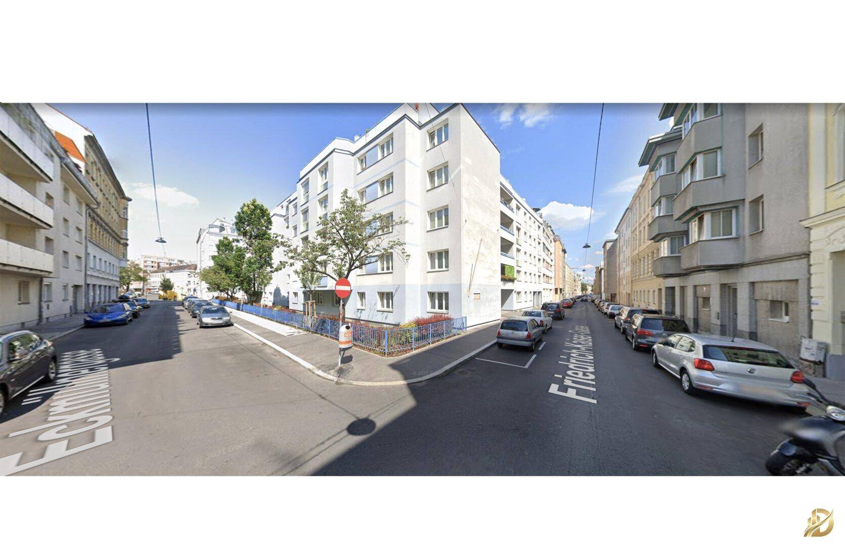 Straßenansicht eines Wohngebäudes mit parkenden Autos und Bäumen unter blauem Himmel.
