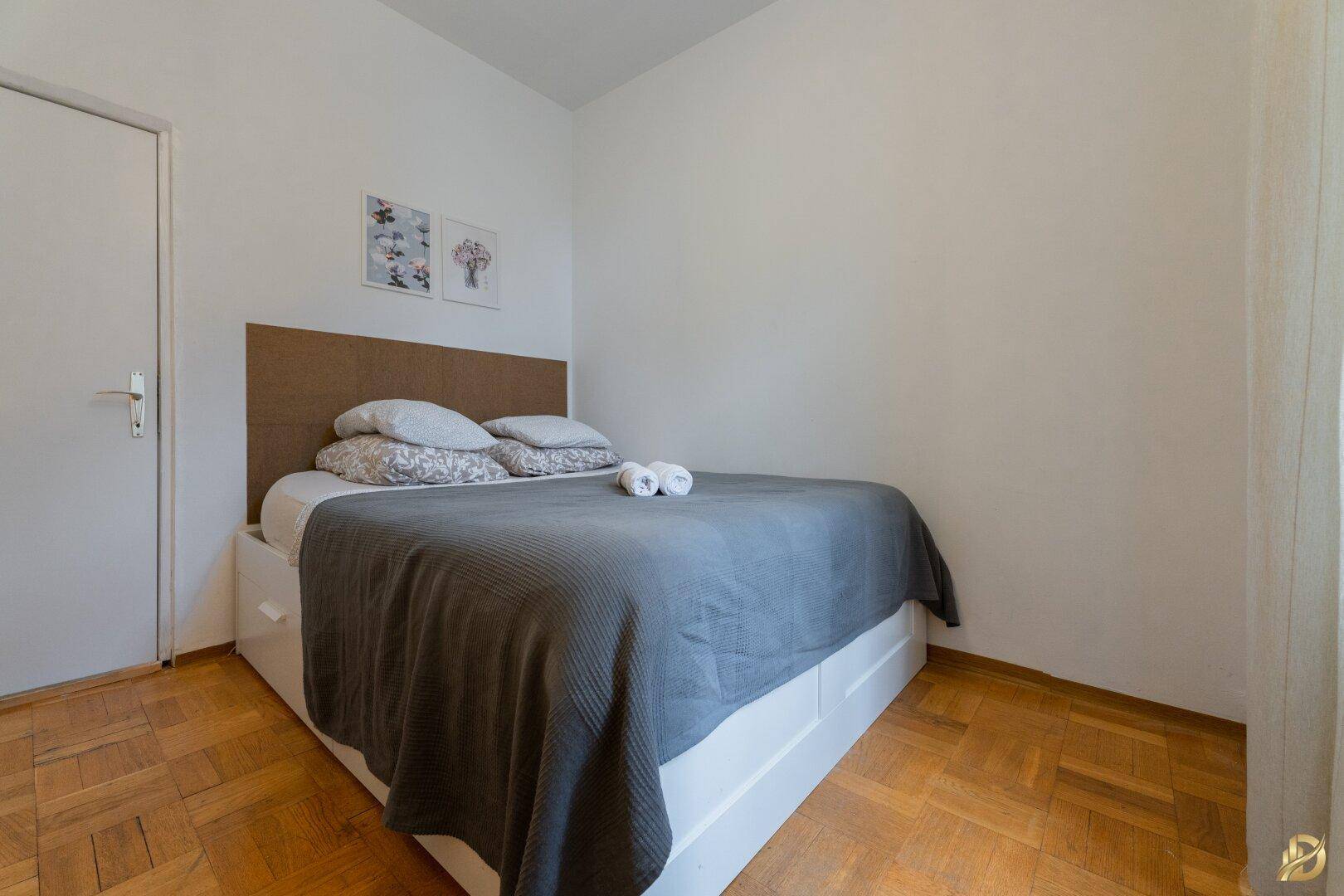 Schlafzimmer mit Doppelbett und Stauraum, Parkettboden und heller Einrichtung.