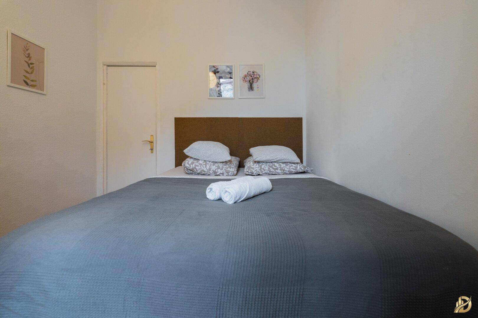 Schlafzimmer mit Doppelbett, Holzkopfteil und Parkettboden, hell und freundlich gestaltet.