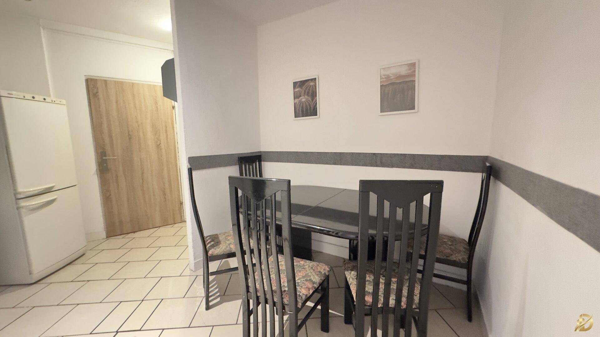 Essbereich mit dunklem Tisch und Stühlen, Fliesenboden und heller Wandgestaltung.