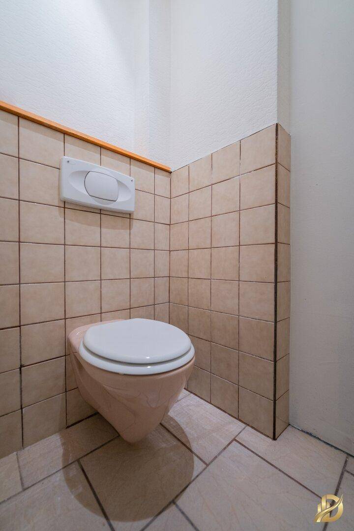 Separate Toilette mit Wand-WC und hellen Fliesen, sauber und funktional.