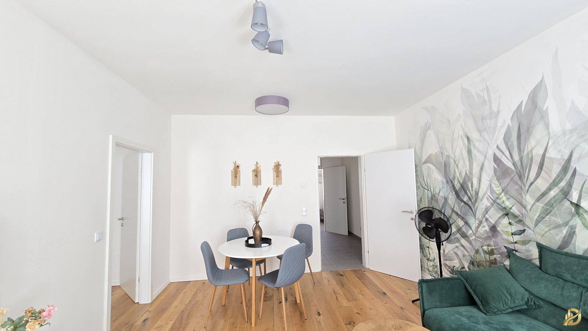 Offener Wohn- und Essbereich mit Holzboden und floraler Wanddekoration, modern und hell gestaltet.