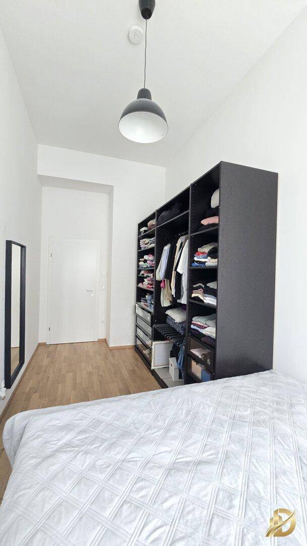 Schlafzimmer mit praktischem offenem Kleiderschrank und gemütlichem Bett, ideal für Stauraum.
