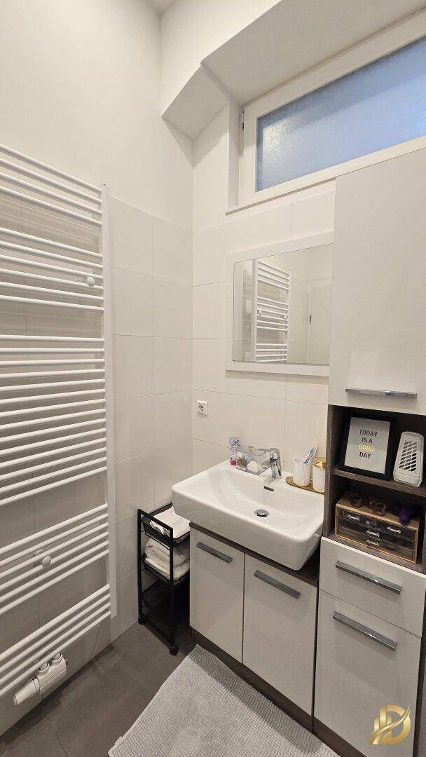 Badezimmer mit Waschbecken, Spiegelschrank und beheiztem Handtuchhalter für Komfort.