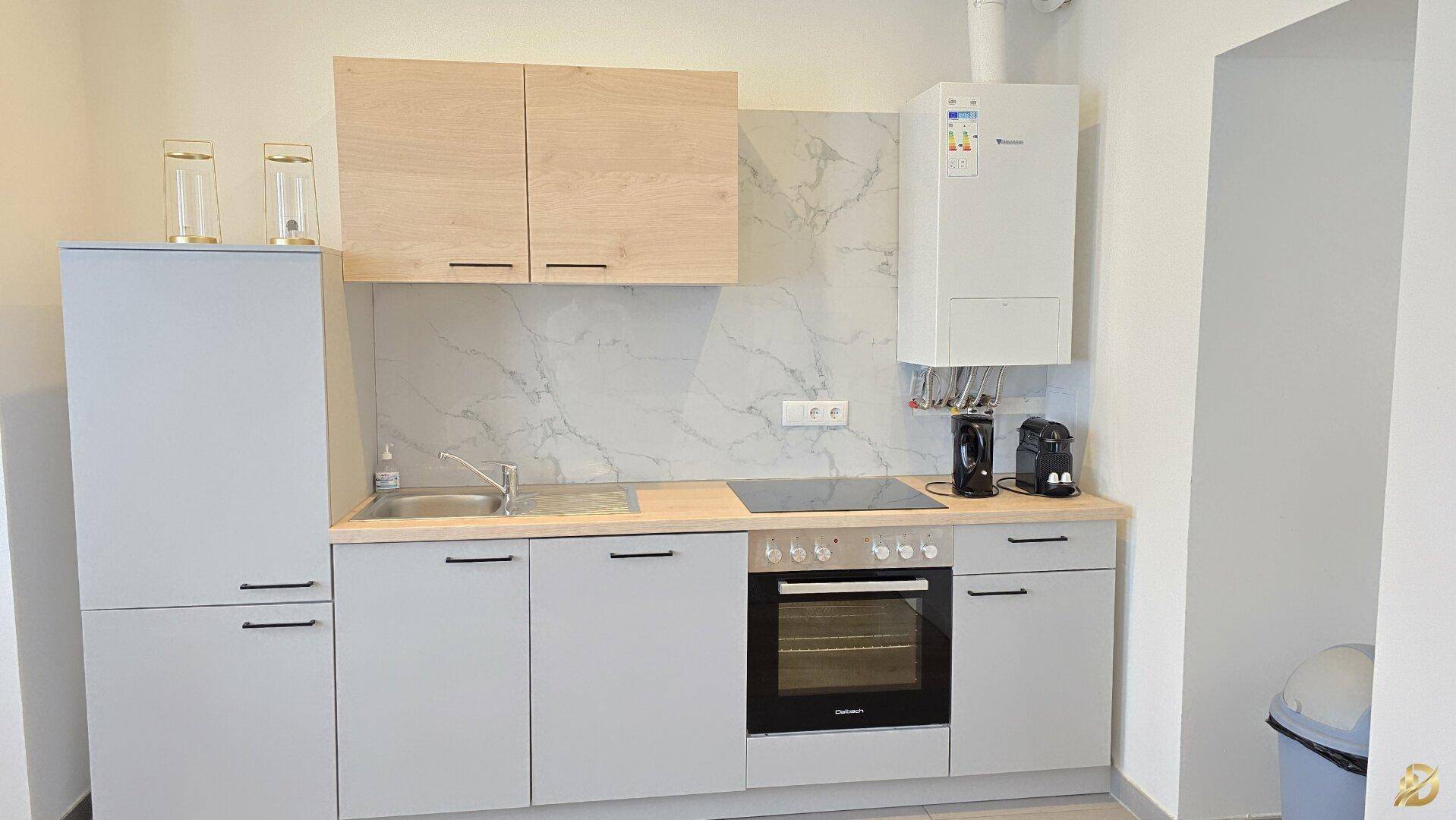 Moderne Einbauküche mit hellen Schränken, Induktionskochfeld und Backofen.