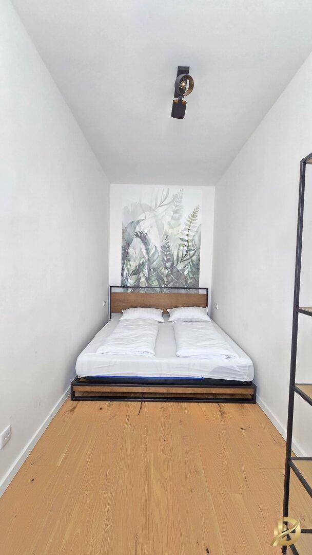 Schlafzimmer mit Doppelbett, Holzboden und dekorativer Wandtapete.