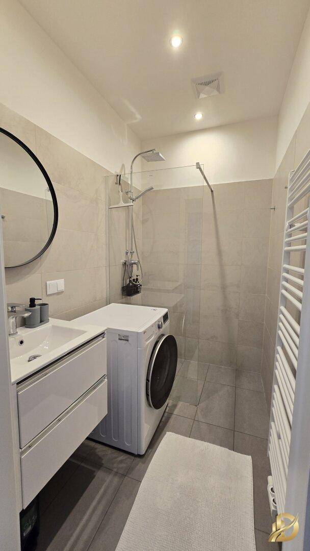 Modernes Badezimmer mit Dusche, Waschmaschine und beheiztem Handtuchhalter.