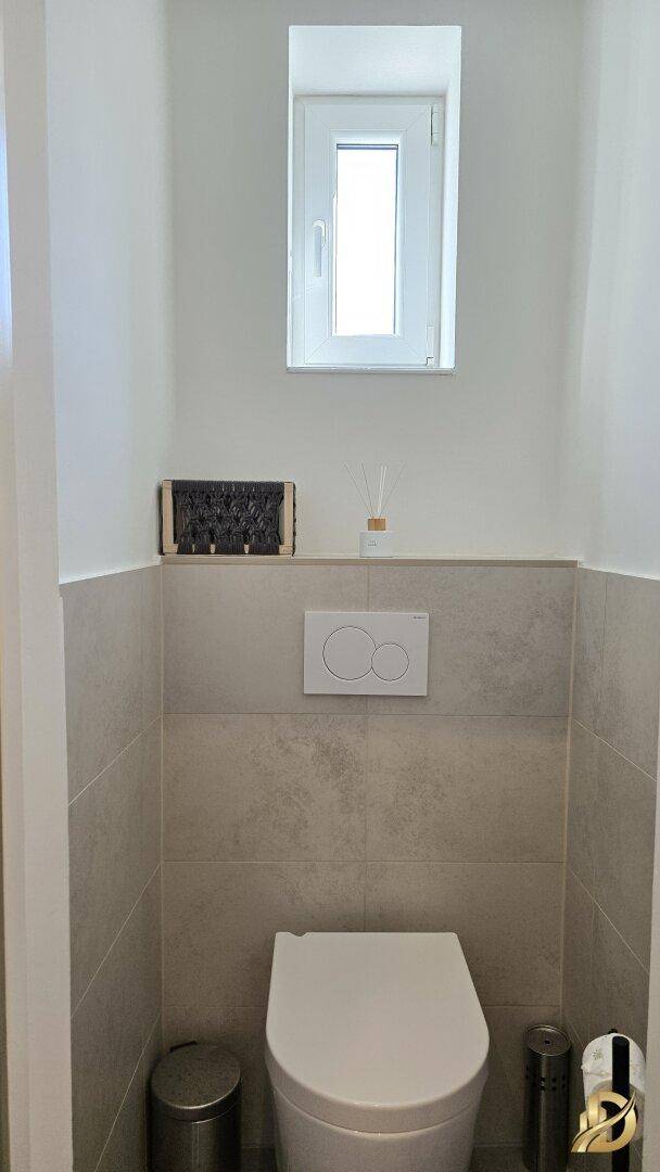 Separate Toilette mit Fenster und Wand-WC.