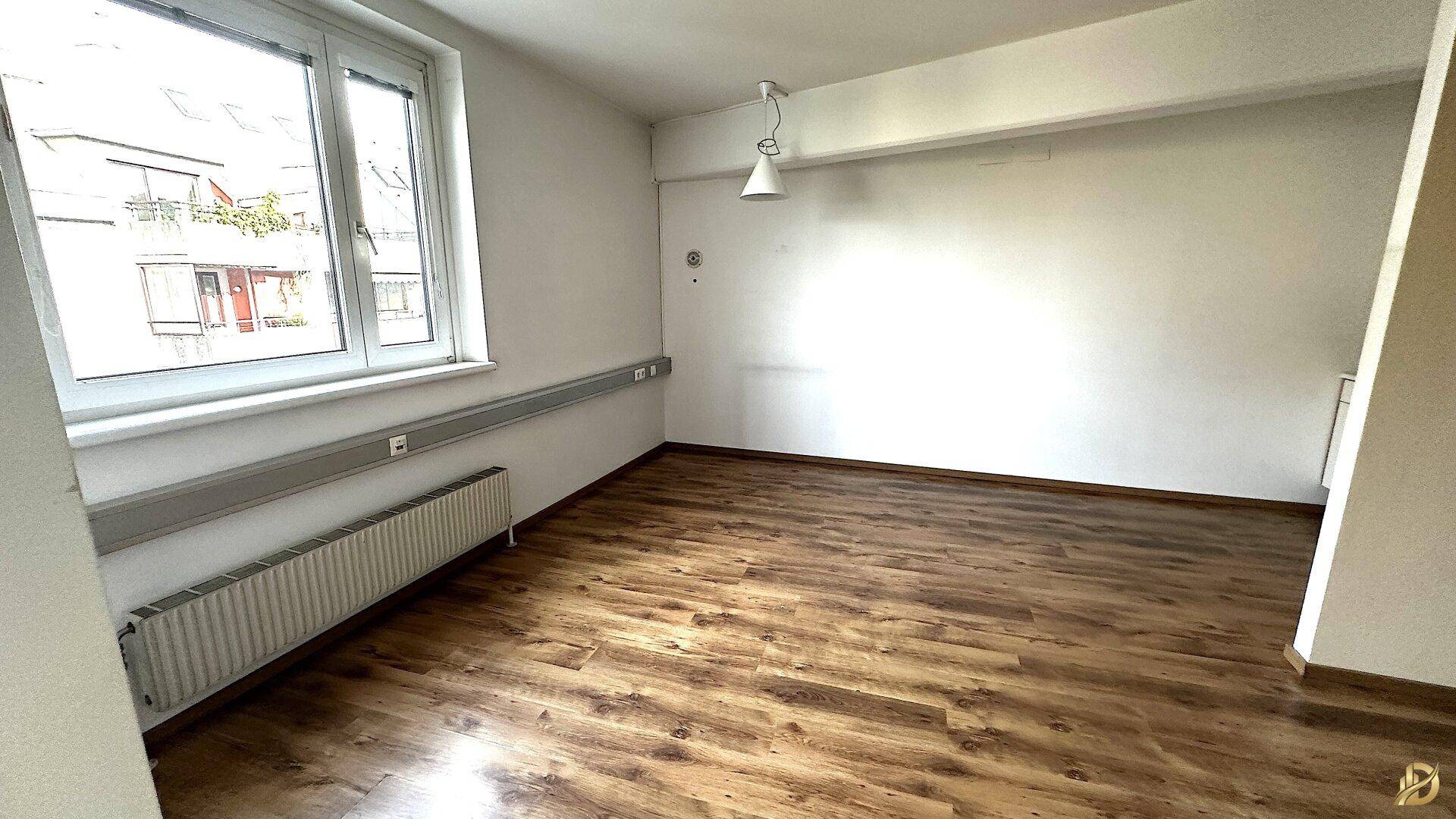 Büro mit Laminatboden und einem großen Fenster, das viel natürliches Licht in den Raum bringt.