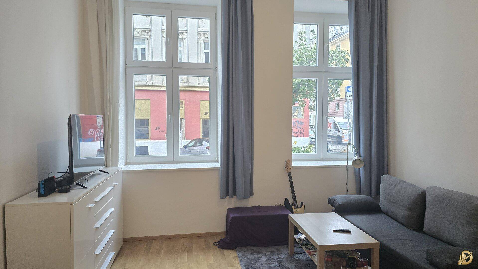 Gemütliches Wohnzimmer mit Sofa, Fernseher und Blick auf die Straße.