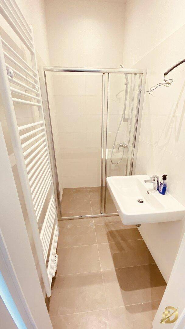 Modernes Badezimmer mit Duschkabine, Waschbecken und beheiztem Handtuchhalter.