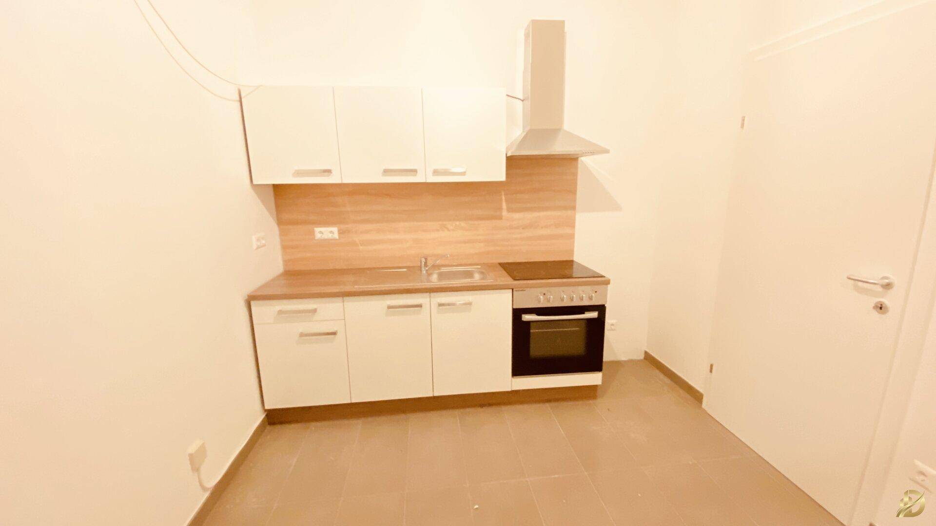 Moderne Küchenzeile mit weißen Schränken, Holz-Arbeitsplatte und integriertem Backofen.