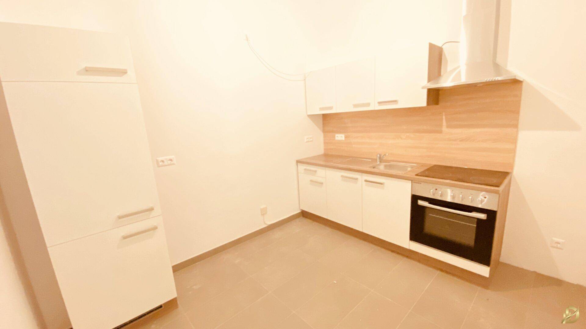 Moderne Küchenzeile mit weißen Schränken, Holz-Arbeitsplatte und integriertem Kühlschrank.