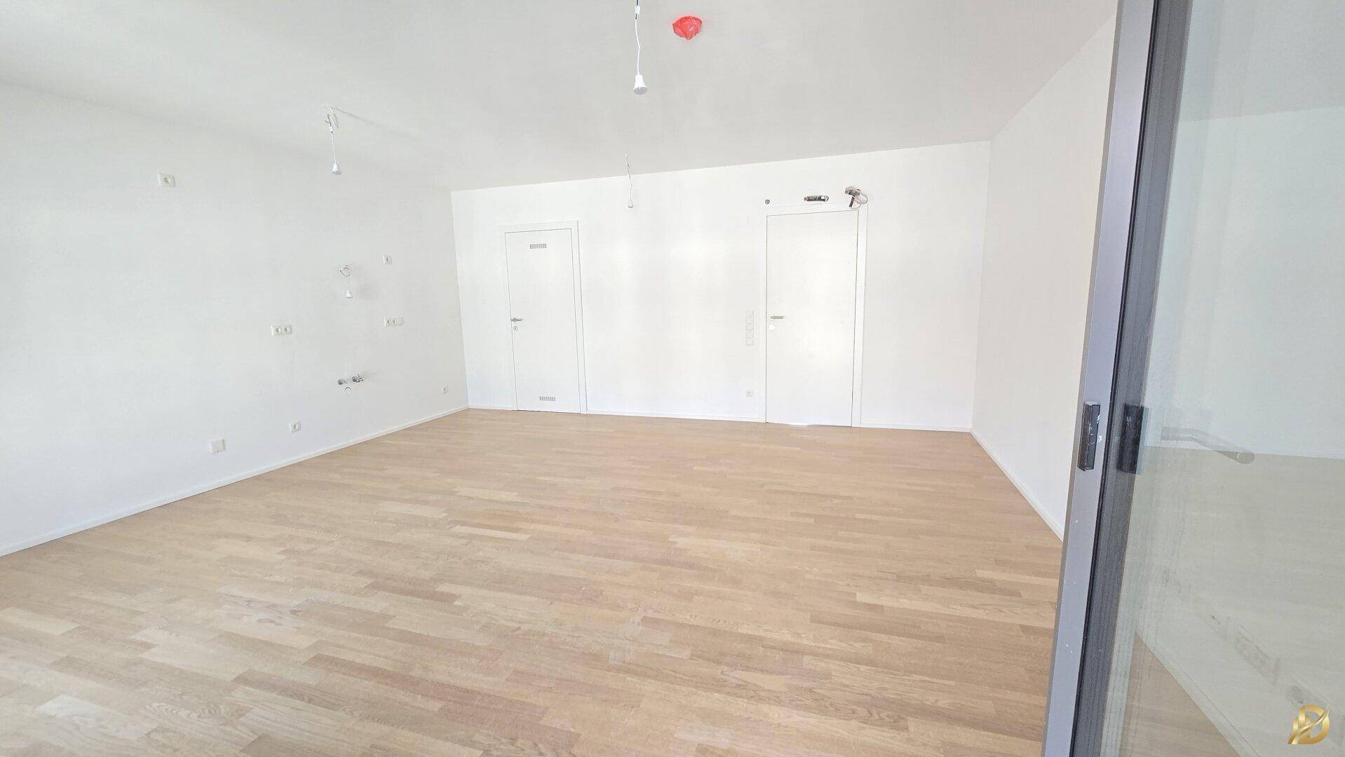 Geräumiges Zimmer mit hellem Parkettboden und zwei weißen Türen, bietet vielseitige Nutzungsmöglichkeiten.