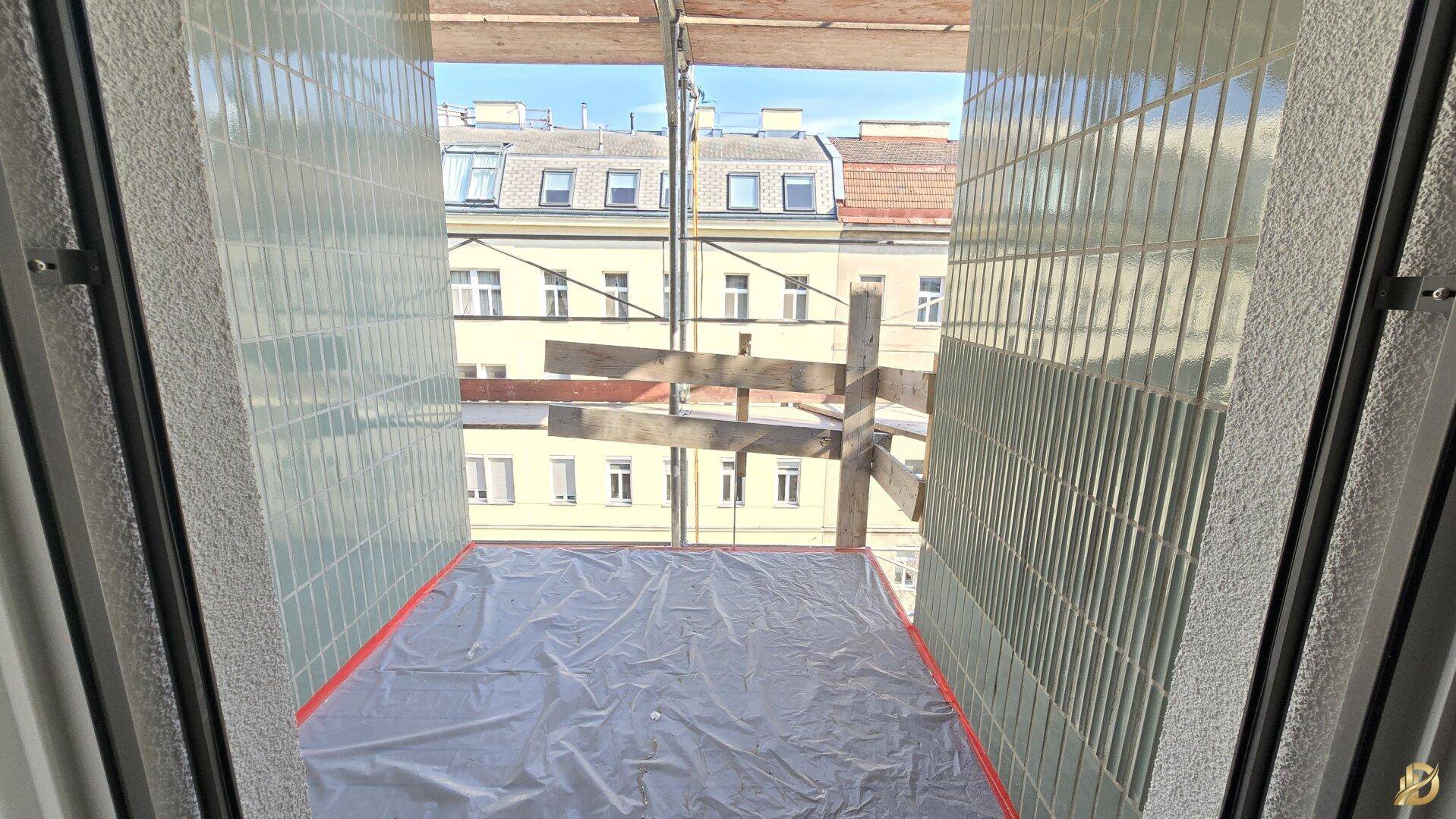 Blick aus dem Fenster auf eine Baustelle mit Gerüst und umliegenden Gebäuden.