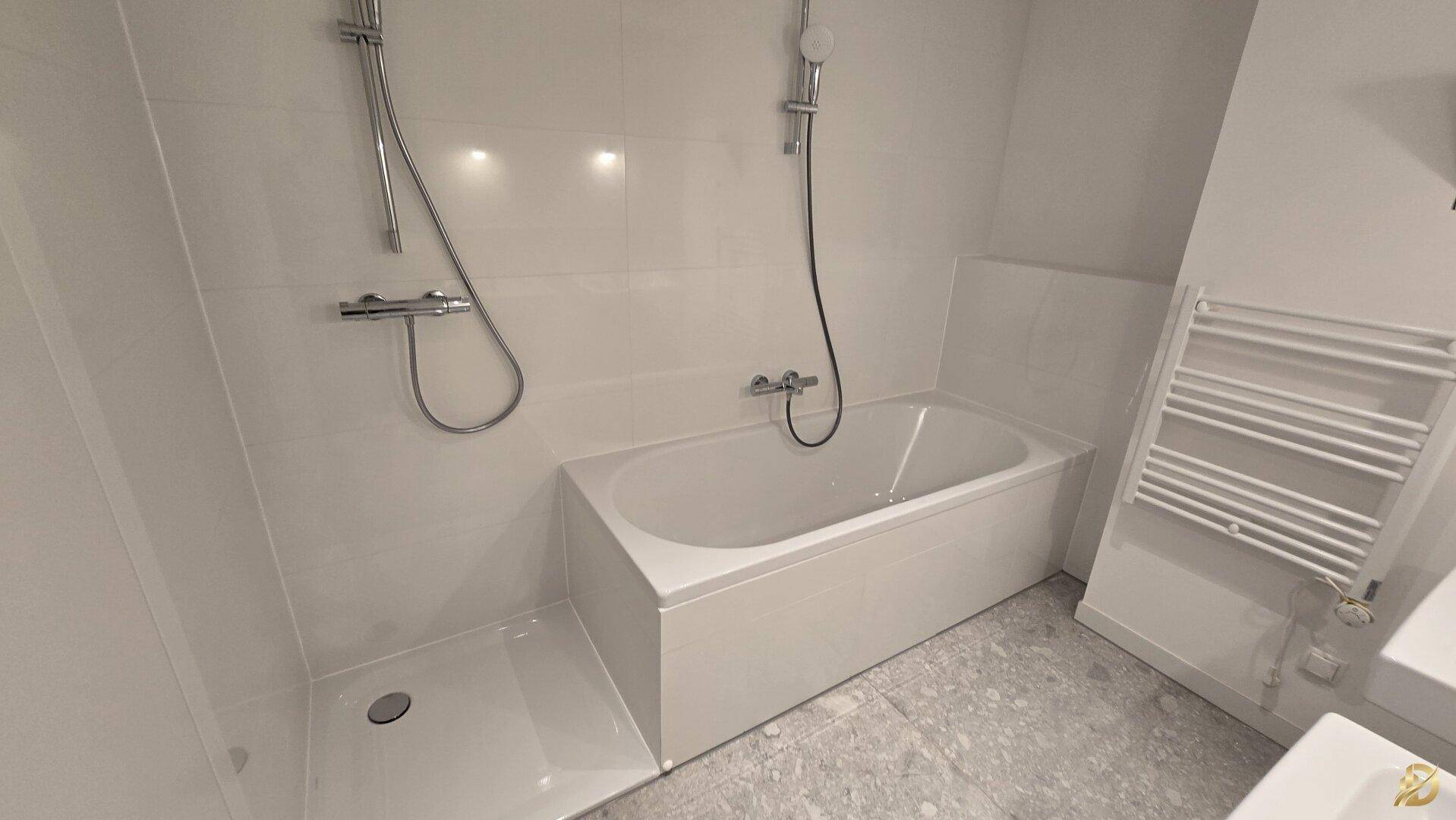 Modernes Badezimmer mit weißen Fliesen, Badewanne, Duschbereich und beheiztem Handtuchhalter.
