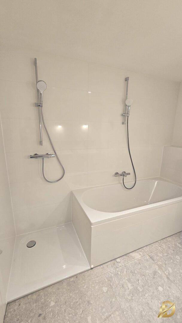 Helles Badezimmer mit weißen Wandfliesen, integrierter Badewanne und separatem Duschbereich.