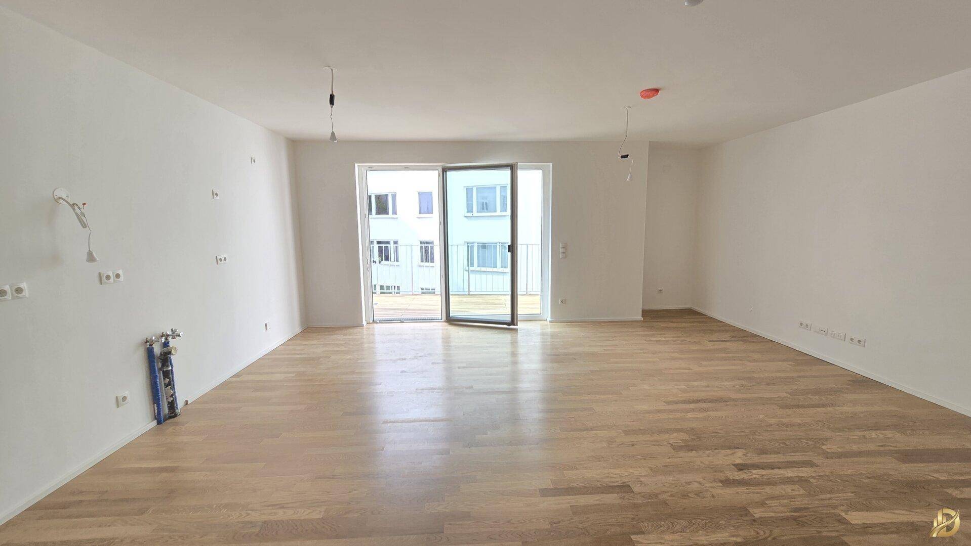 Geräumiger, heller Wohnbereich mit Parkettboden und großen Schiebetüren, die viel Licht hereinlassen.