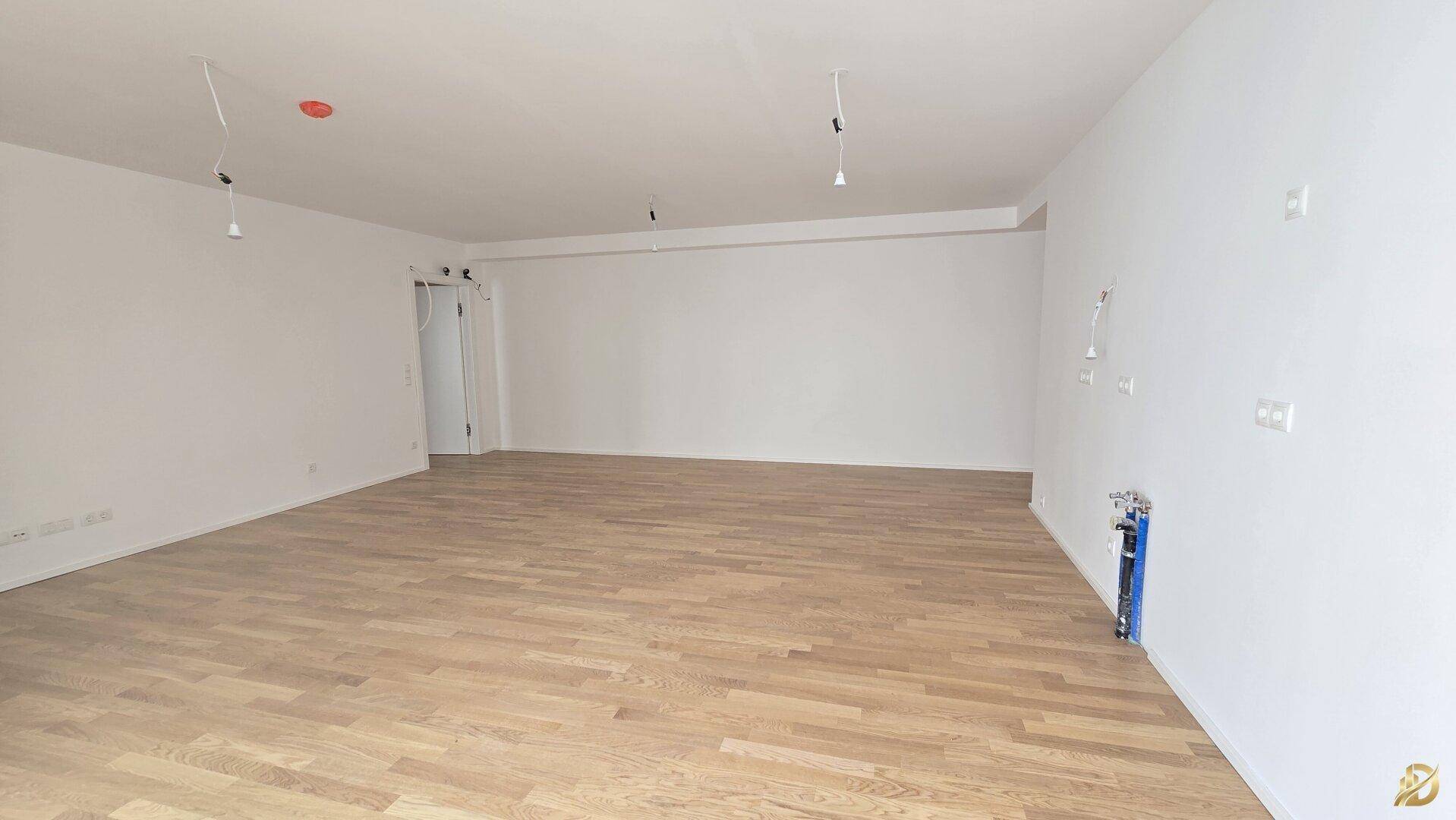 Heller Wohnraum mit Parkettboden und weißen Wänden, vorbereitet für weitere Installationen.