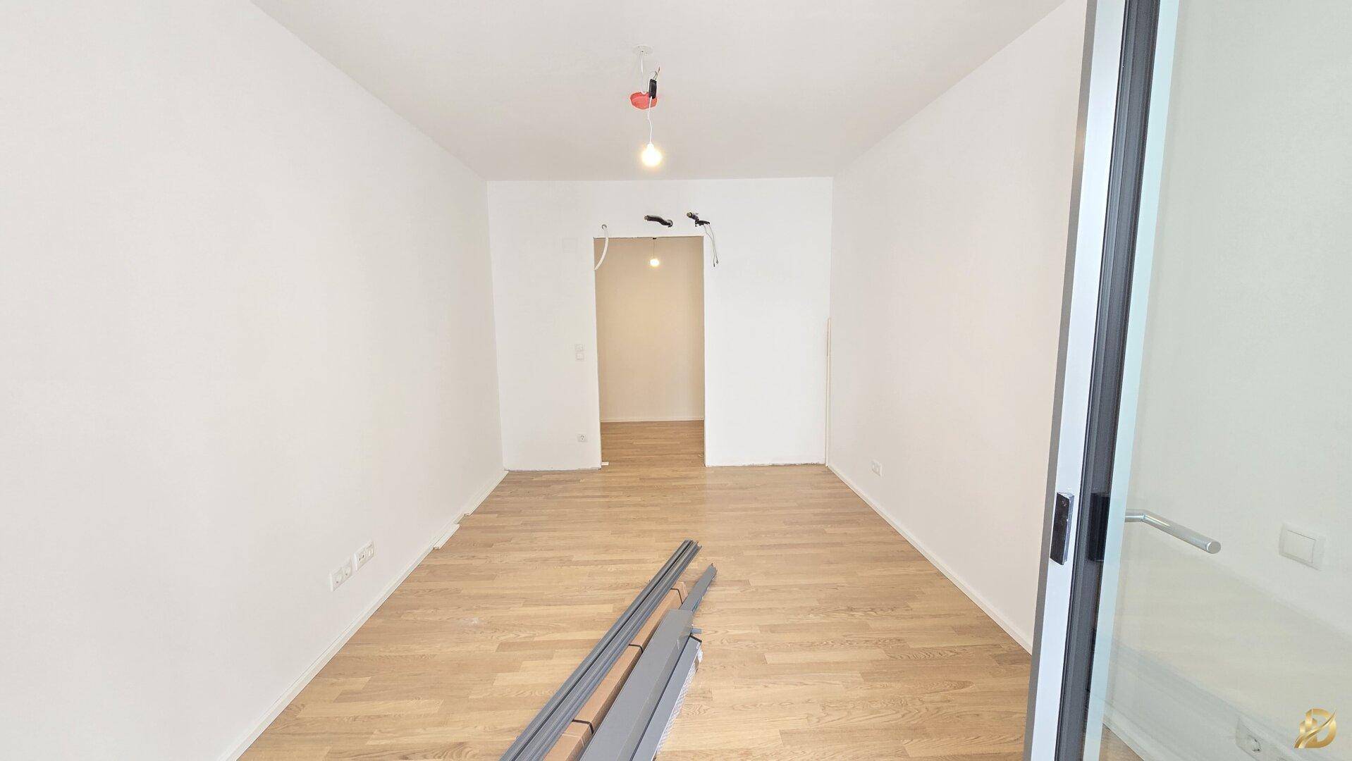 Helles Zimmer mit Parkettboden und Glasschiebetür, ideal als Schlaf- oder Arbeitszimmer.