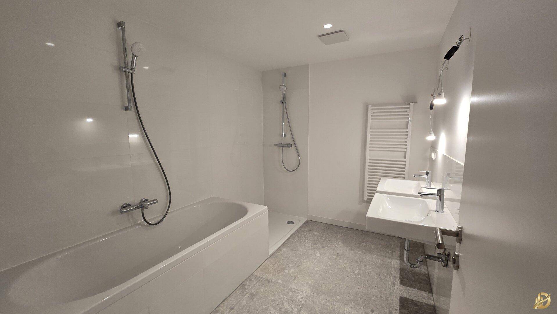 Modernes Badezimmer mit Badewanne, Dusche, Doppelwaschbecken und beheiztem Handtuchhalter.