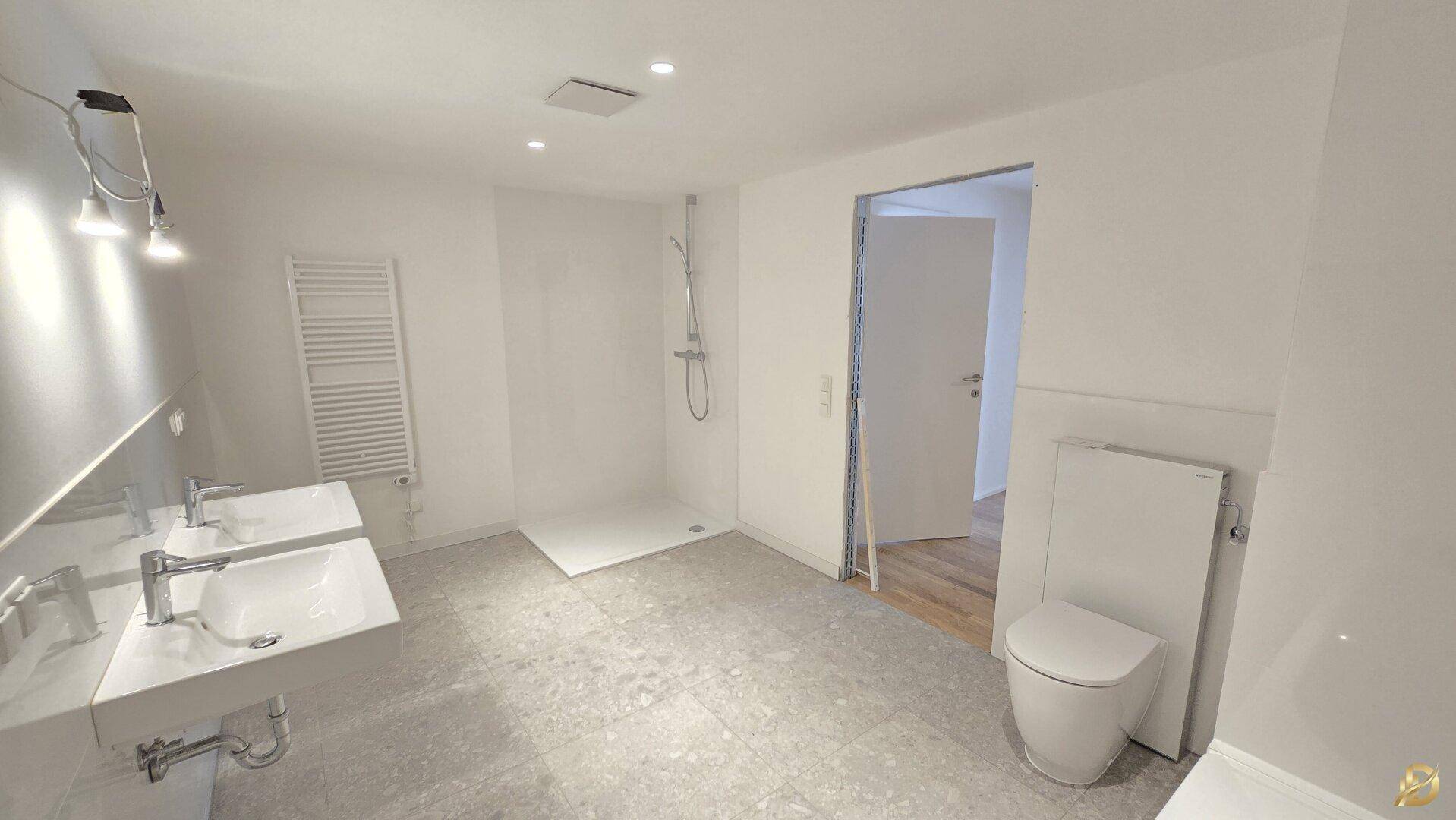 Modernes Badezimmer mit ebenerdiger Dusche, Doppelwaschbecken und wandhängendem WC.