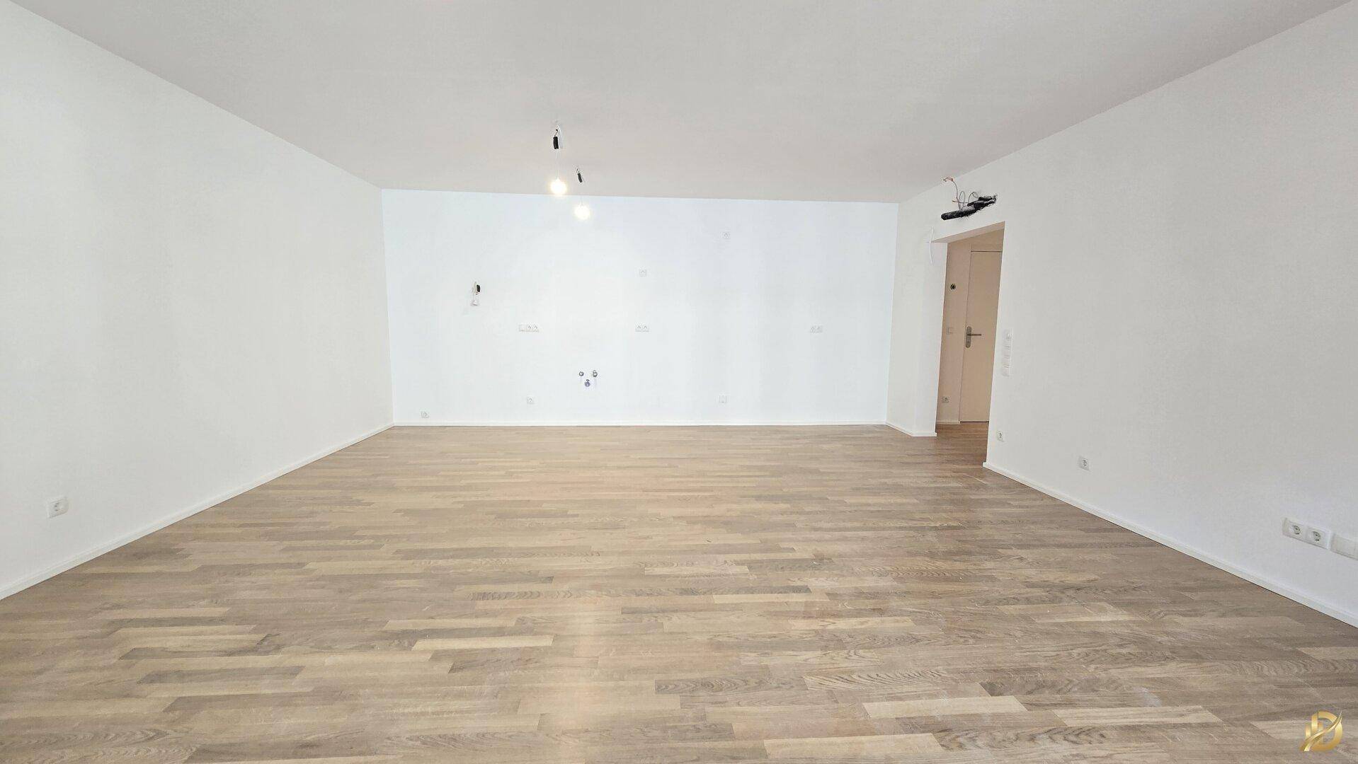 Geräumiger, heller Raum mit Parkettboden und Zugang zu einem Flur.