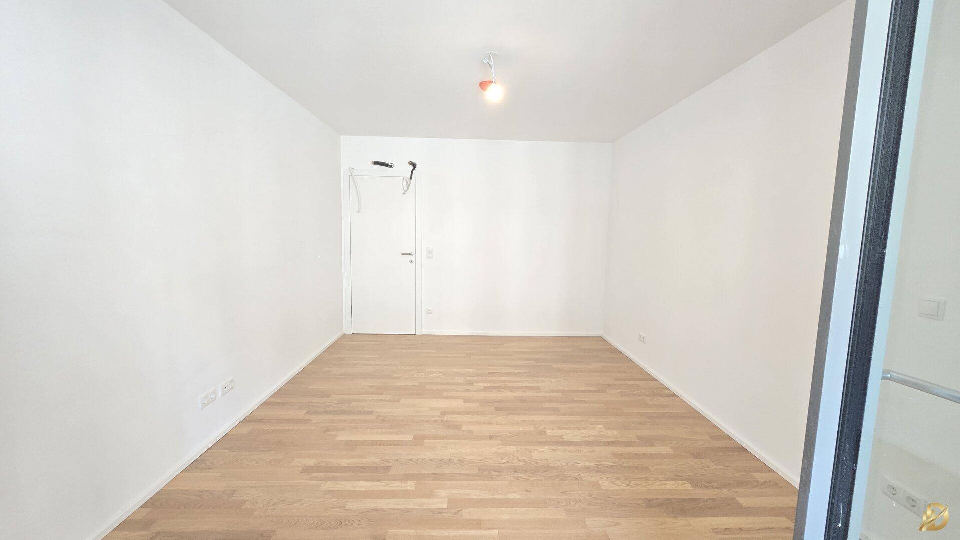 Helles Schlafzimmer mit Parkettboden und einer modernen Glastür.