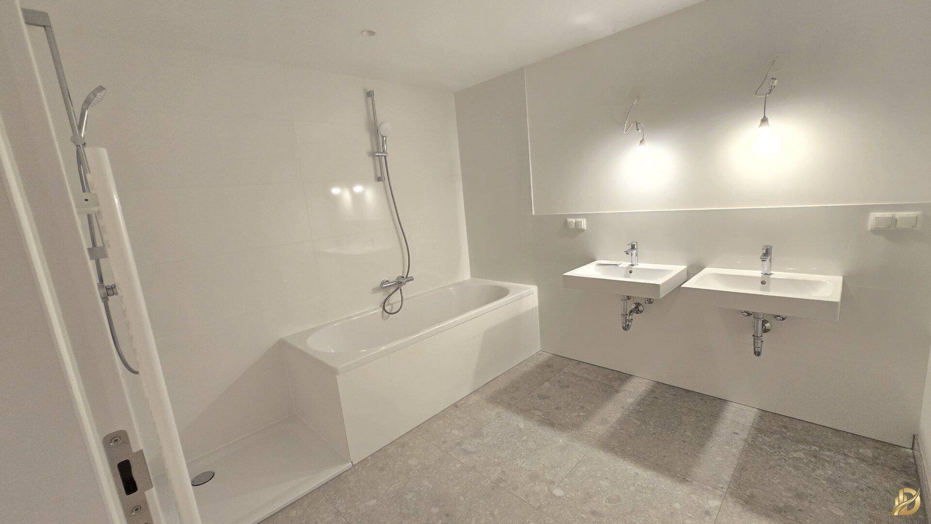 Modernes Badezimmer mit Badewanne, Dusche und Doppelwaschbecken.