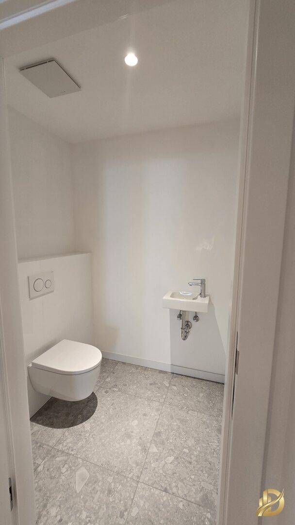 Modernes Gäste-WC mit wandhängender Toilette und kleinem Waschbecken.