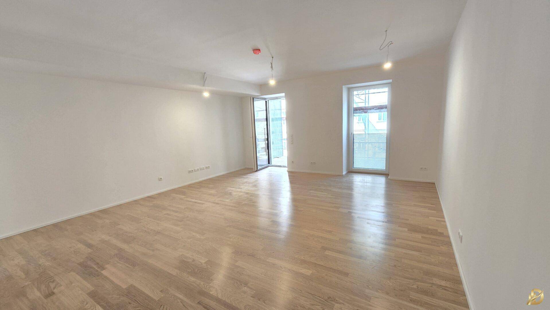 Helles Wohnzimmer mit Parkettboden und Zugang zu einem französischen Balkon.
