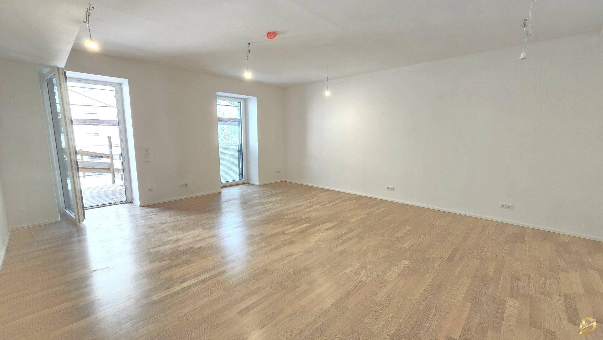 Geräumiges Wohnzimmer mit Parkettboden und viel natürlichem Licht.