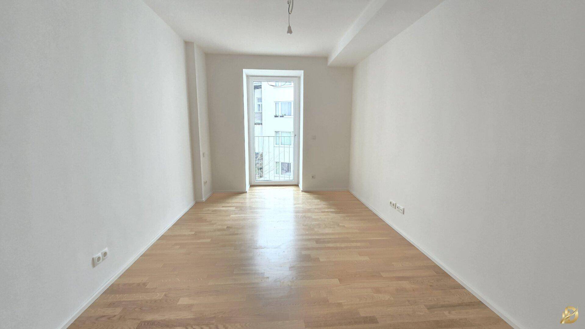 Helles Schlafzimmer mit Parkettboden und Zugang zu einem Balkon.