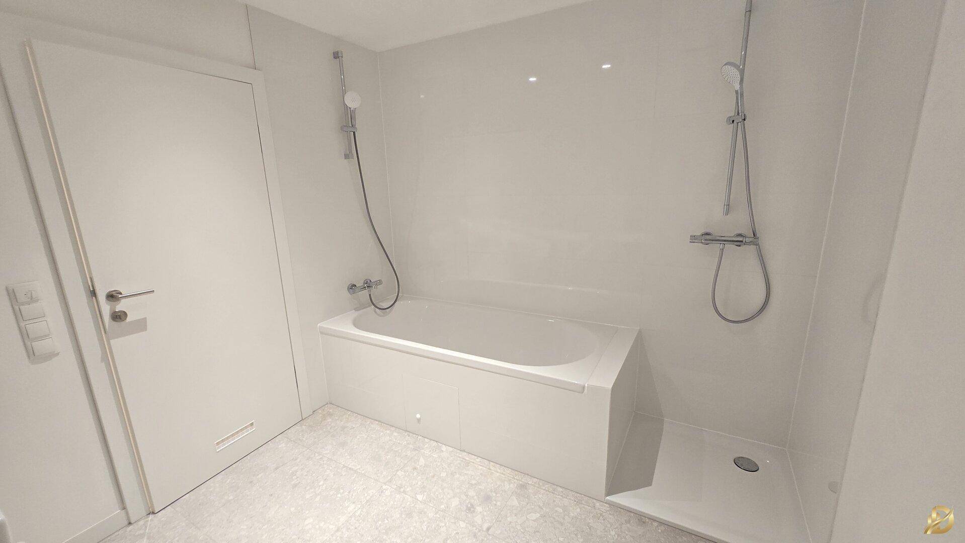 Modernes Badezimmer mit Badewanne, Duschbereich und hellen Fliesen.