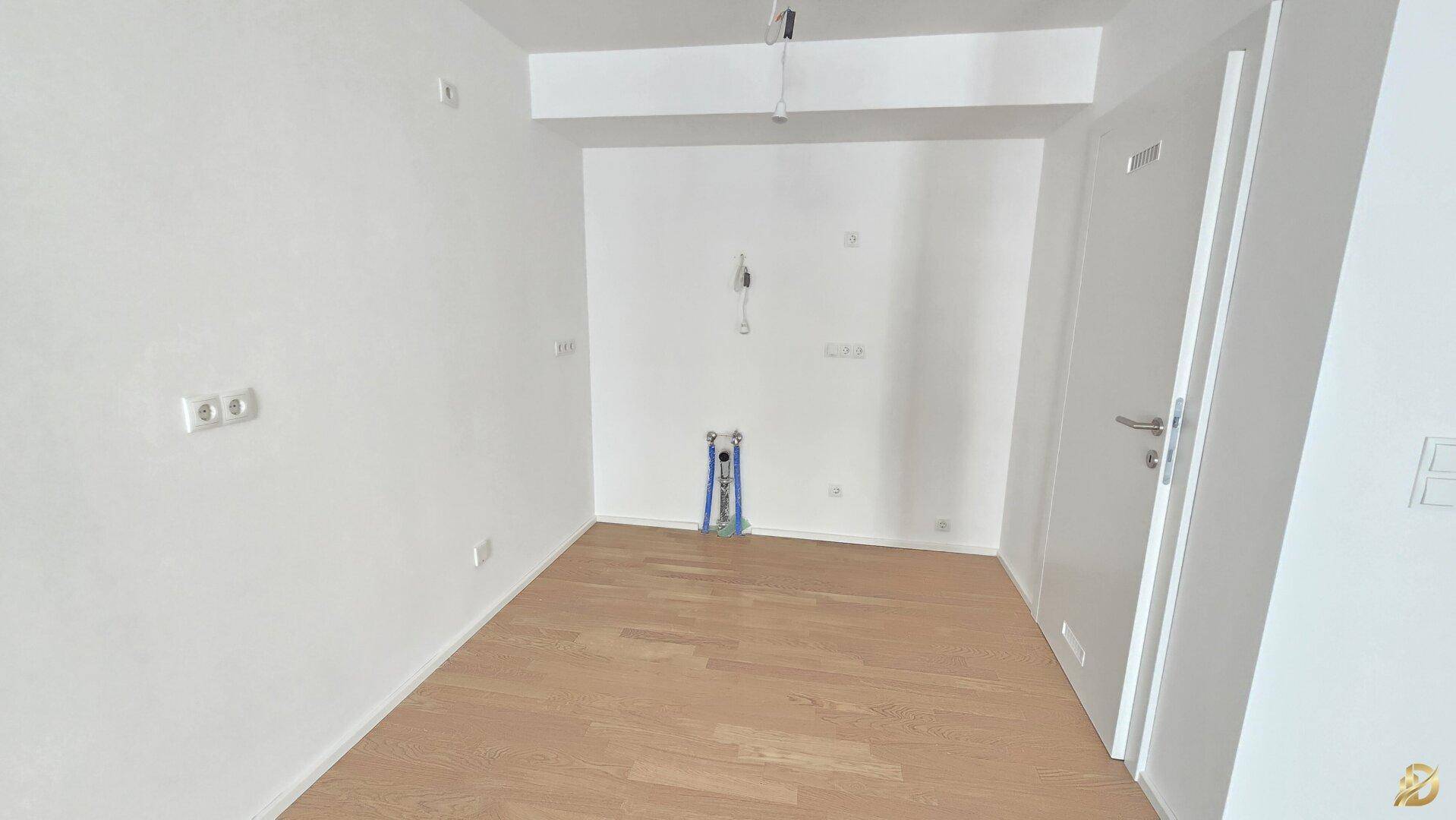 Kleinerer Raum mit Holzparkett und Anschlüssen, ideal für eine kompakte Küche oder einen Hauswirtschaftsraum.
