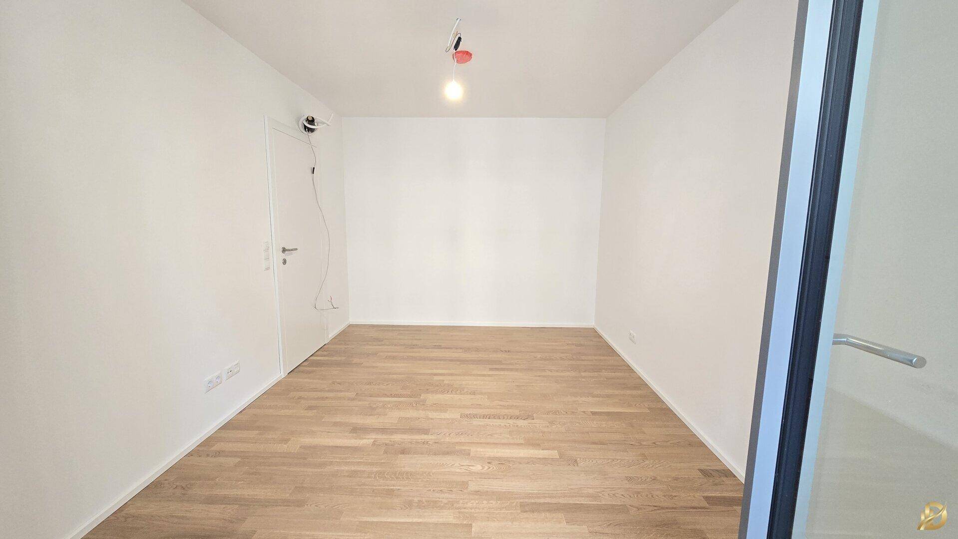 Heller Raum mit Holzparkett und weißen Wänden, geeignet als Schlafzimmer oder Arbeitszimmer.