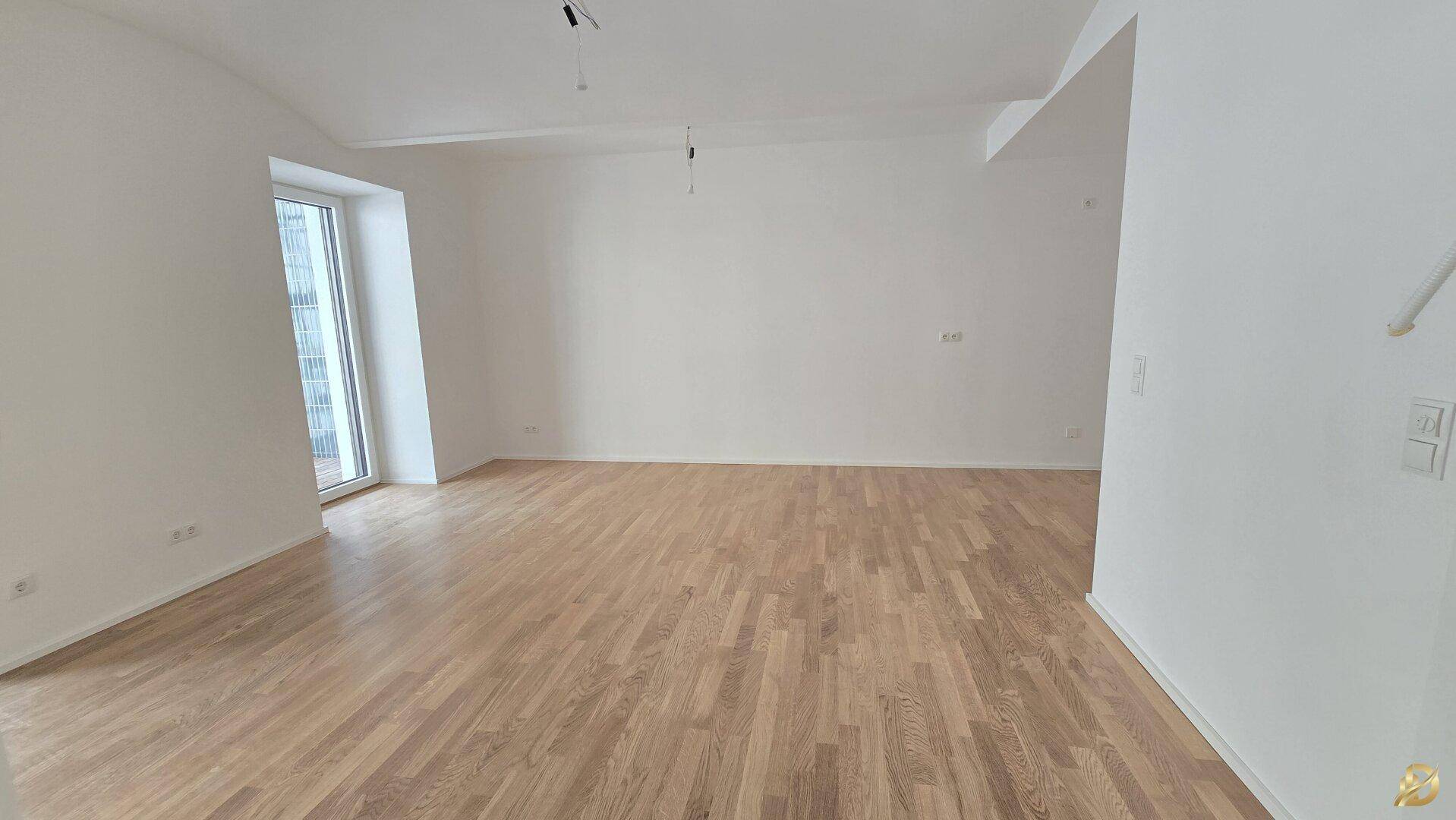 Großzügiger, heller Wohnbereich mit Eichenparkett und Zugang zu einem Balkon oder einer Terrasse.
