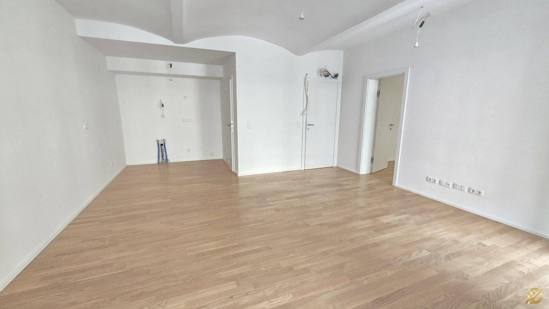 Heller Wohnbereich mit Holzparkett und weißen Wänden, ideal für eine offene Küchenlösung.