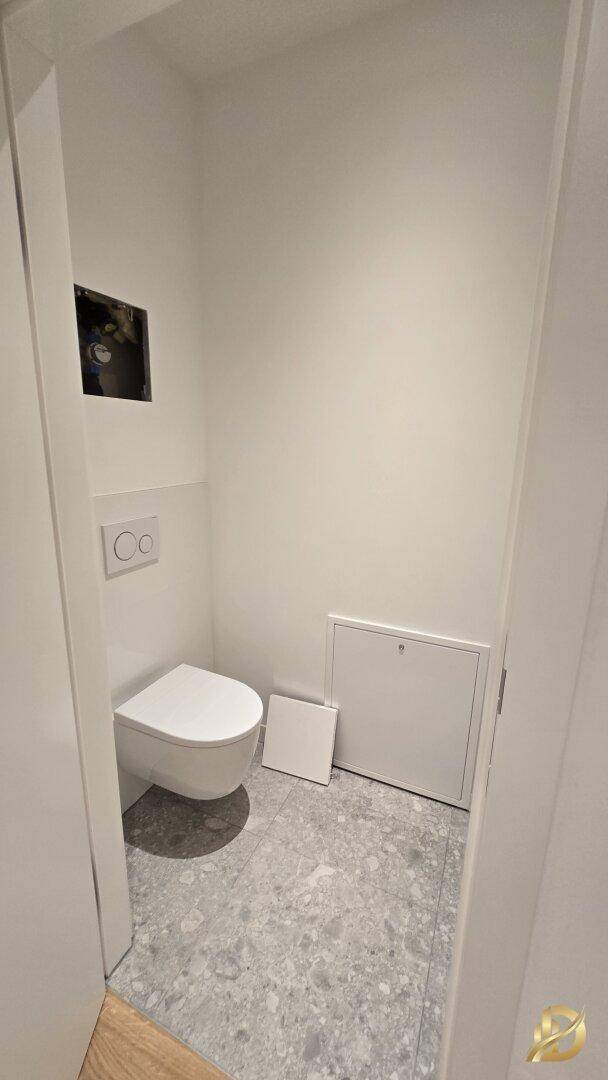 Modernes Gäste-WC mit wandhängender Toilette und grauen Bodenfliesen.