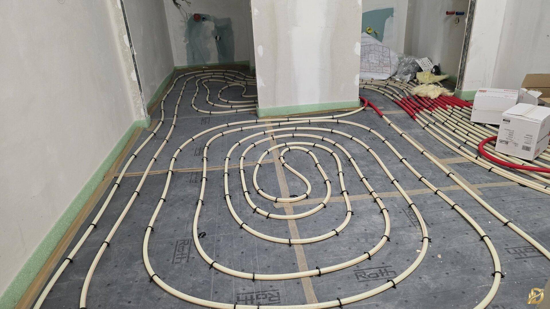 Installation der Fußbodenheizung mit Rohren auf dem Untergrund während der Bauphase.