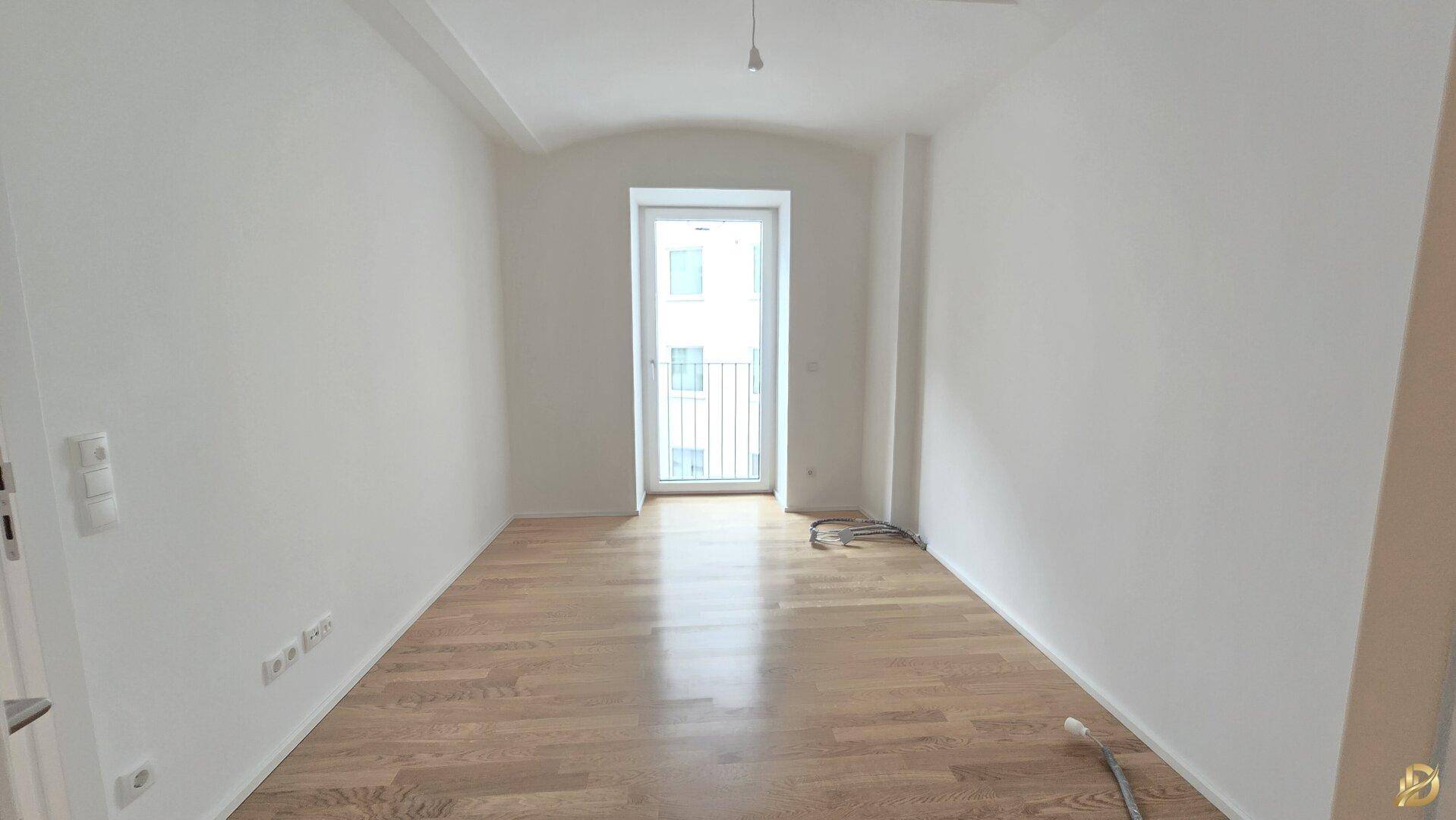 Ruhiges Schlafzimmer mit Holzboden und einem französischen Balkon, ideal für erholsame Nächte.