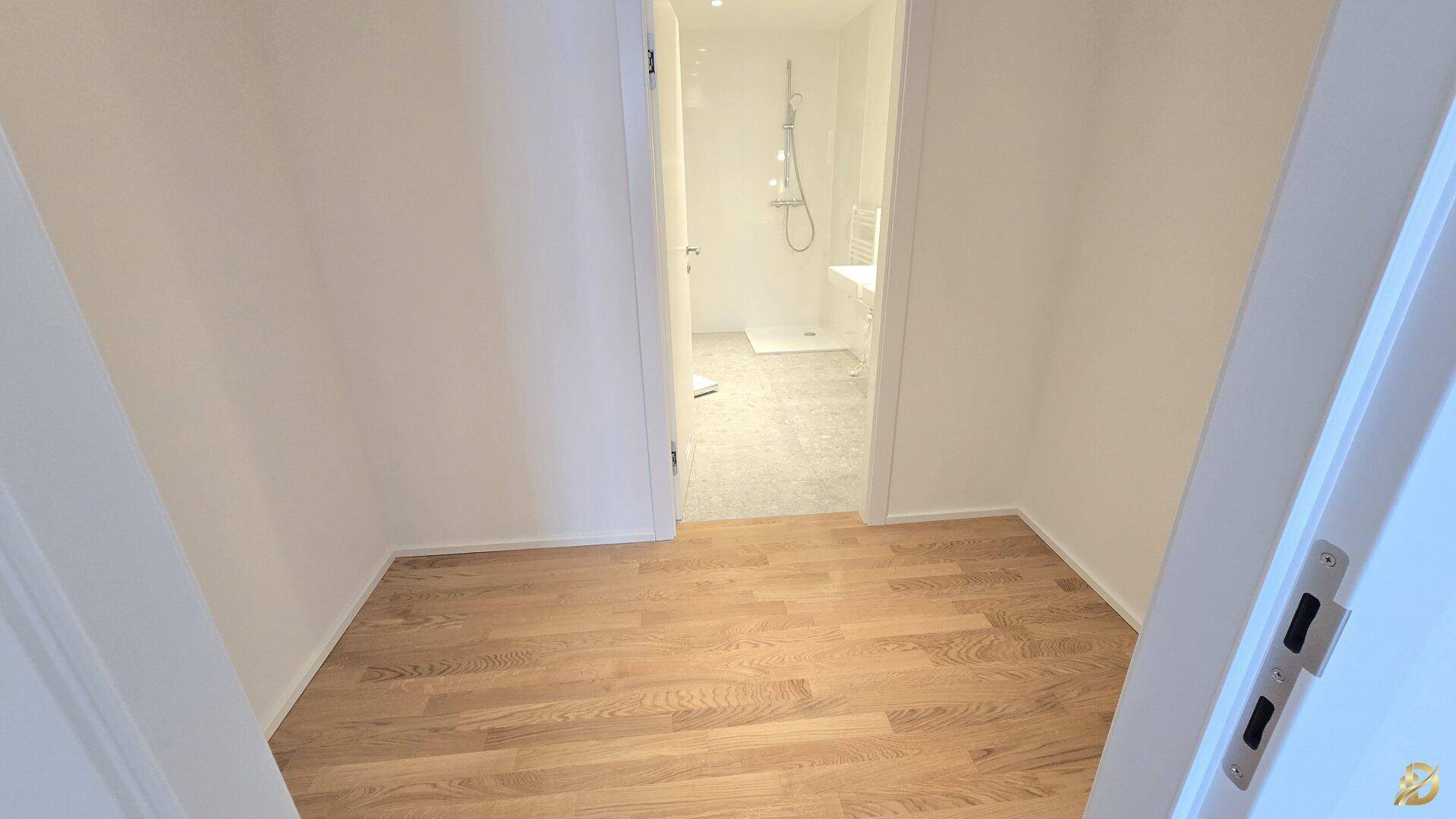 Übergangsbereich mit Holzboden, der zu einem modernen Badezimmer mit Fliesen führt.
