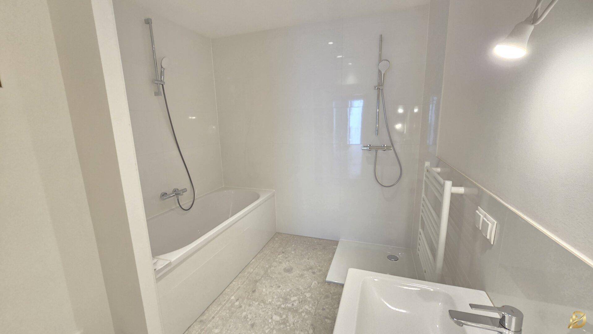 Modernes Badezimmer mit Badewanne, Dusche, Waschbecken und beheiztem Handtuchhalter.