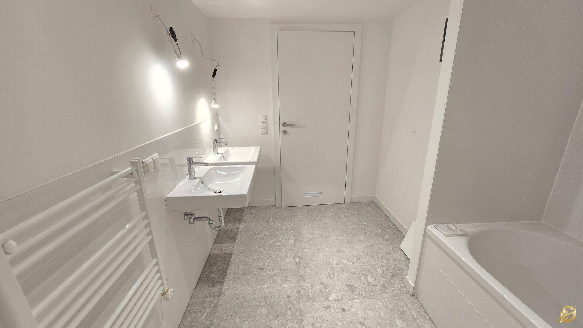 Geräumiges Badezimmer mit Doppelwaschbecken, beheiztem Handtuchhalter und Badewanne.