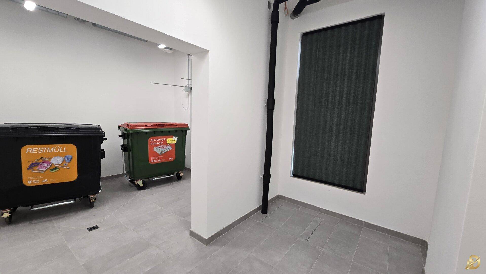 Abfallraum mit Containern für Restmüll und Altpapier, ausgestattet mit Fliesenboden.