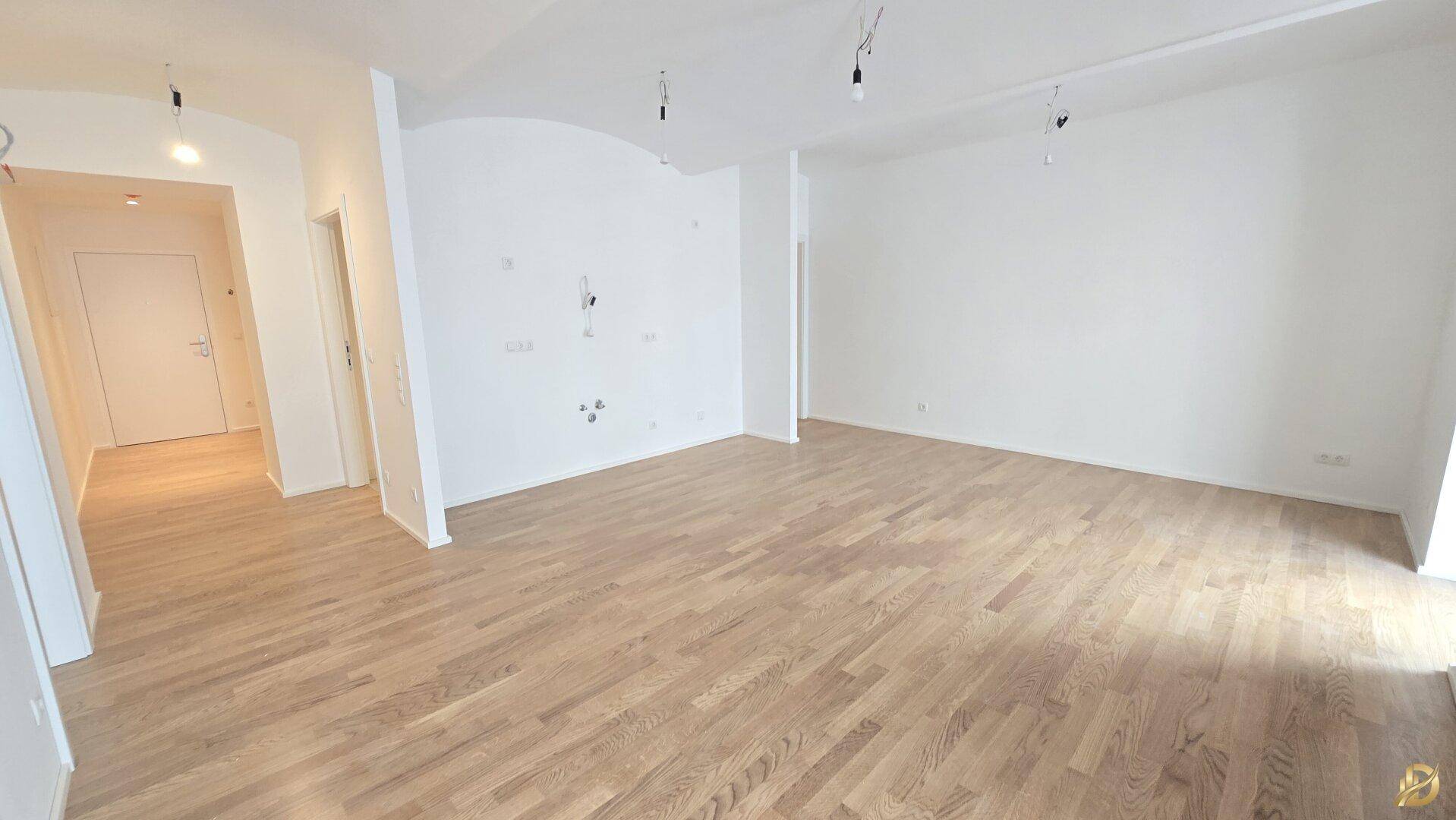 Offener Wohnbereich mit Parkettboden und weiß gestrichenen Wänden, ideal für moderne Einrichtung.